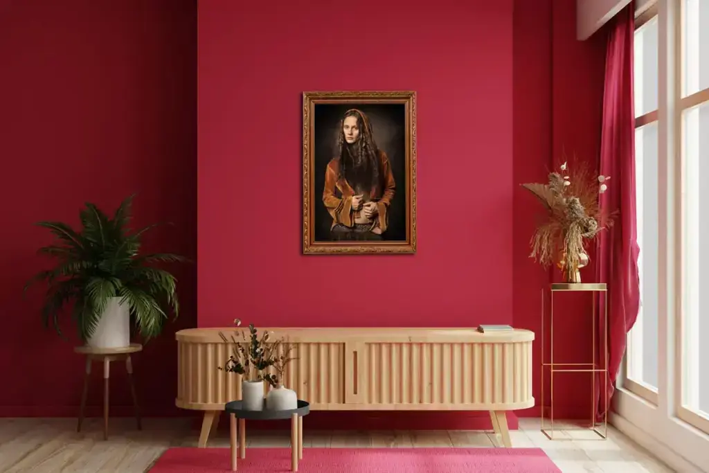 Moderner Raum mit roter Wand, Holzboden, hellem Sideboard und einem Porträt einer sitzenden Frau mit langem Haar und brauner Kleidung in einem vergoldeten Rahmen. Links steht ein grüner Pflanzenkübel auf einem kleinen Holztablett, rechts ein hoher goldener Blumenständer mit getrockneten Blumen neben großen Fenstern mit roten Vorhängen.