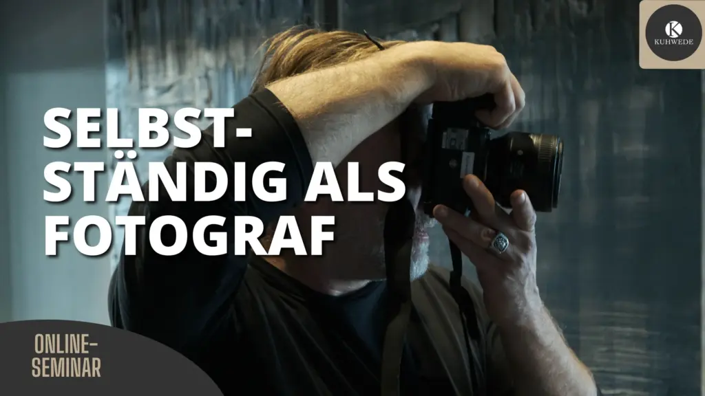 Mann mit grauem Bart und schwarzem Oberteil fotografiert mit Kamera, dazu Text "Selbstständig als Fotograf" und "Online-Seminar"